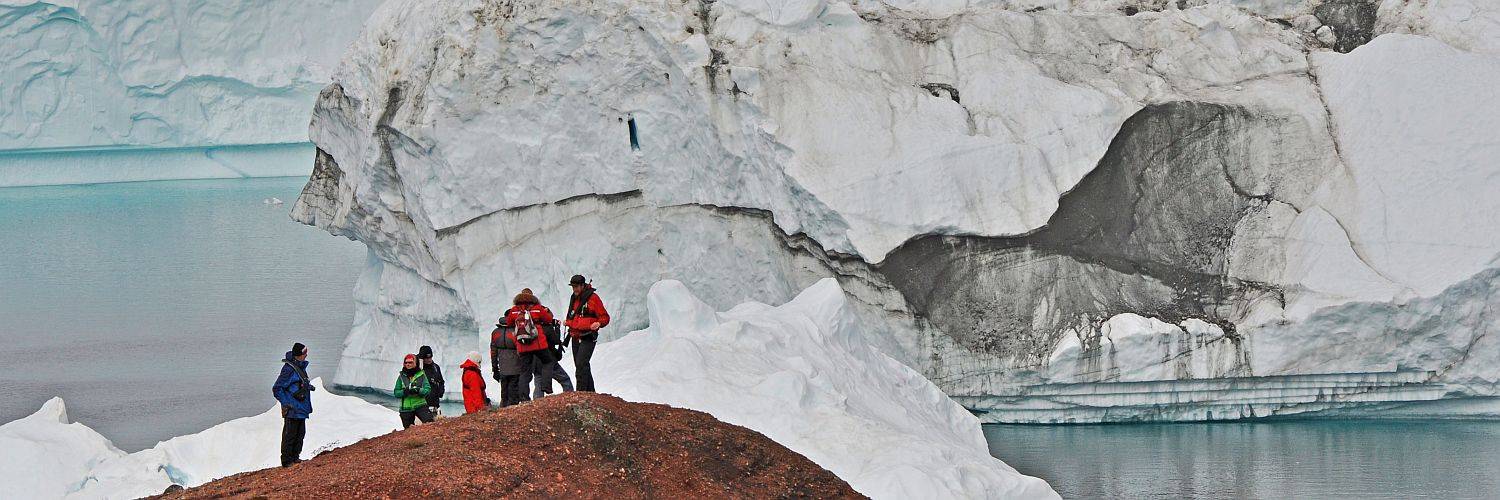 Im Rode Fjord bieten sich Reisenden extreme Farbkontraste zwischen Eisbergen und dem roten Sandstein der Felsen